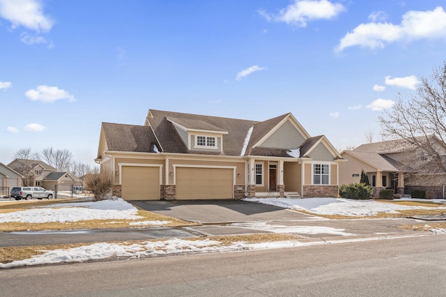 townhome / multi-family property featuring aphalt driveway, stone siding, and an attached garage