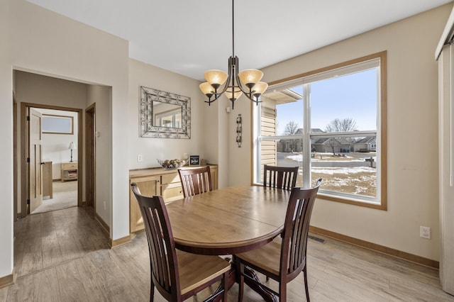 dining area featuring baseboards, an inviting chandelier, and light wood finished floors