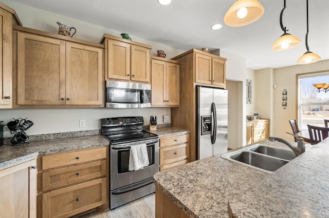 kitchen featuring recessed lighting, a sink, hanging light fixtures, stainless steel appliances, and light wood-style floors