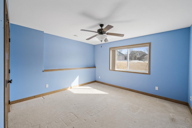 carpeted spare room featuring baseboards and ceiling fan