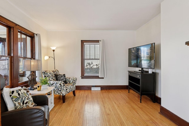 living area featuring visible vents, ornamental molding, baseboards, and wood-type flooring