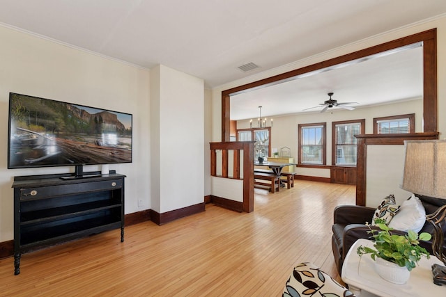 living area featuring visible vents, baseboards, light wood-style flooring, and ornamental molding