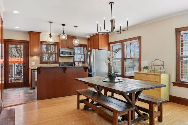 dining space with baseboards, light wood finished floors, recessed lighting, crown molding, and a chandelier