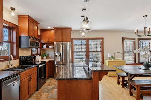 kitchen featuring dark stone countertops, a sink, appliances with stainless steel finishes, tasteful backsplash, and a center island