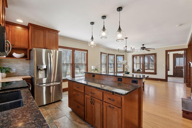 kitchen featuring backsplash, a center island, ornamental molding, appliances with stainless steel finishes, and brown cabinetry