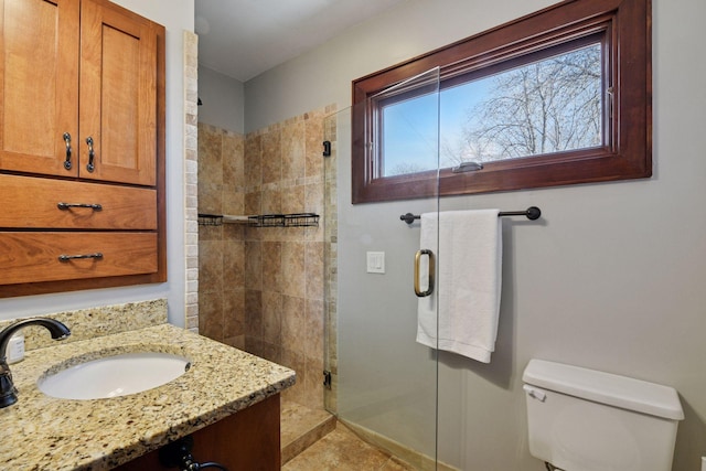 bathroom with baseboards, toilet, vanity, and a shower stall