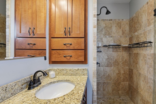 full bath with a tile shower and vanity