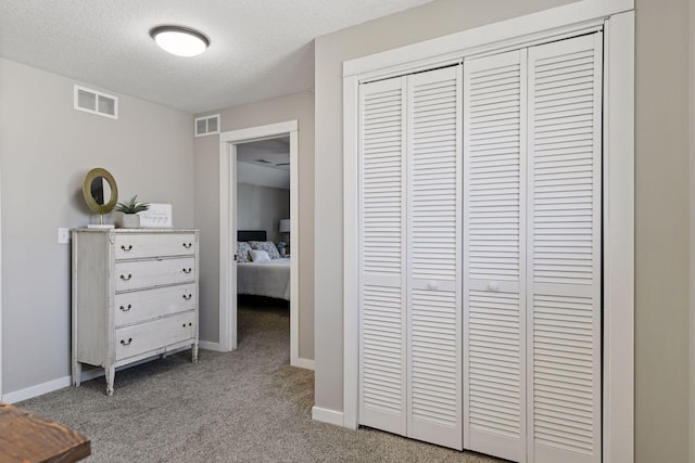 carpeted bedroom featuring visible vents, baseboards, a textured ceiling, and a closet