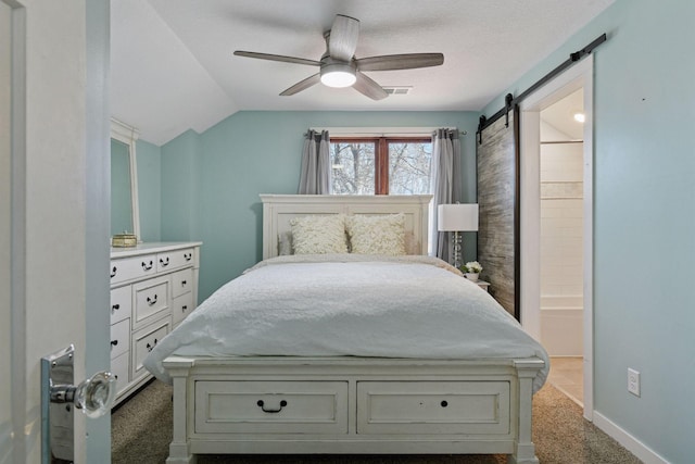 bedroom with visible vents, connected bathroom, dark carpet, lofted ceiling, and a barn door