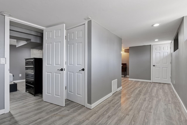 corridor with light wood finished floors, visible vents, recessed lighting, and baseboards