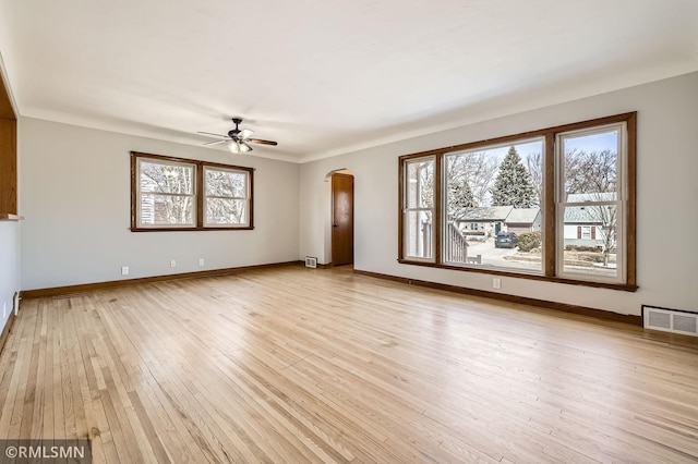 spare room with light wood-style flooring, plenty of natural light, a ceiling fan, and visible vents