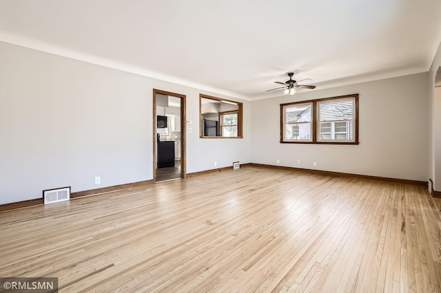 empty room with light wood finished floors, visible vents, baseboards, and a ceiling fan