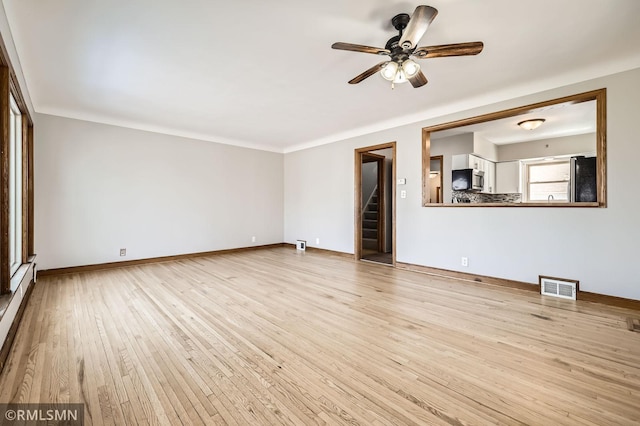 unfurnished living room featuring visible vents, stairway, light wood finished floors, baseboards, and ceiling fan