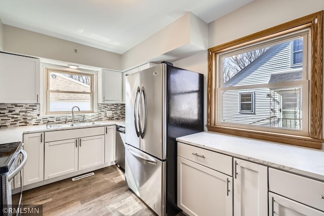 kitchen featuring a sink, stainless steel appliances, decorative backsplash, and white cabinetry