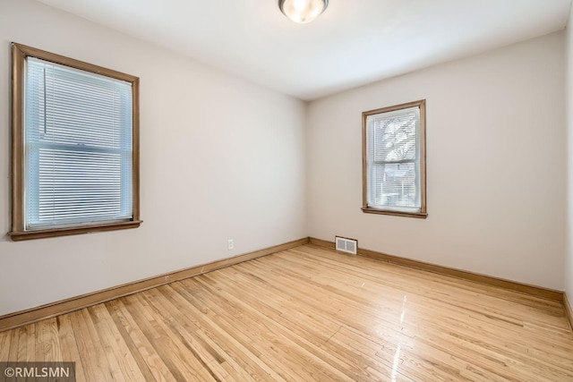 empty room featuring visible vents, baseboards, and wood finished floors