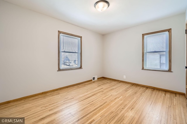 empty room with visible vents, baseboards, and light wood-style floors