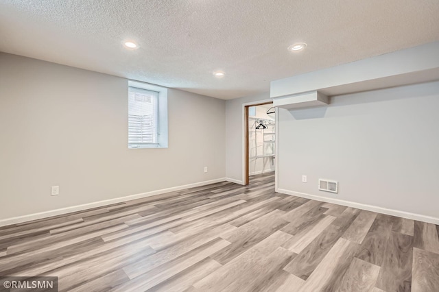 basement featuring wood finished floors, visible vents, baseboards, recessed lighting, and a textured ceiling