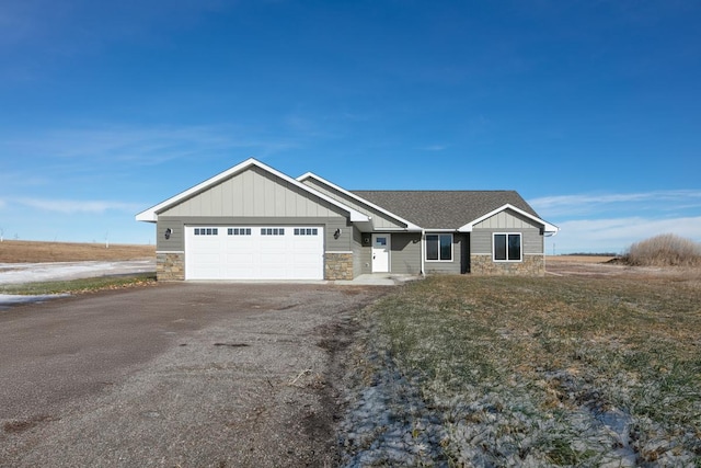 view of front of house with aphalt driveway, stone siding, board and batten siding, and a garage