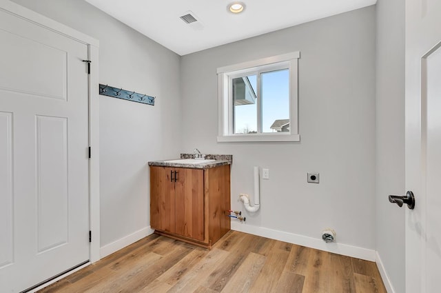 laundry area featuring electric dryer hookup, visible vents, a sink, baseboards, and laundry area