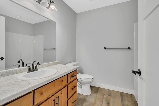 bathroom featuring baseboards, toilet, wood finished floors, and vanity