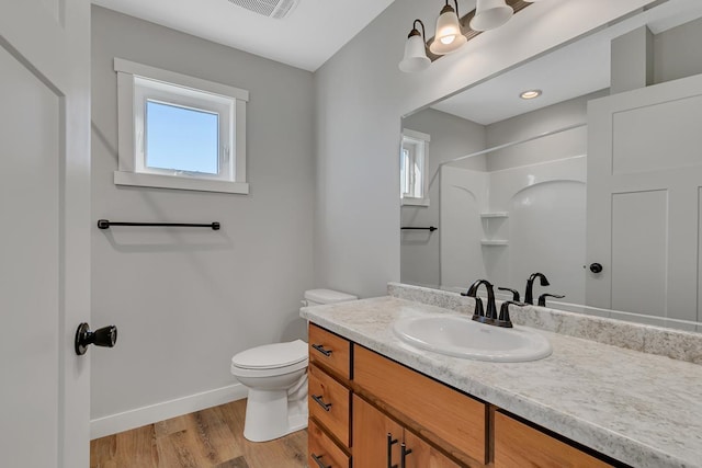 bathroom featuring wood finished floors, toilet, a healthy amount of sunlight, and baseboards