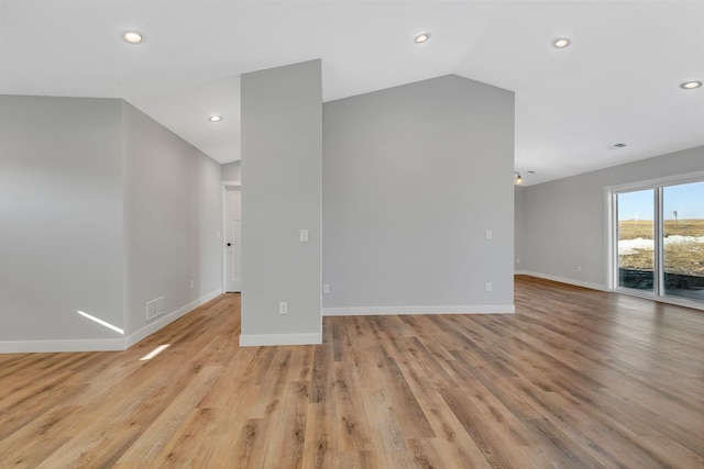 spare room featuring light wood-type flooring, visible vents, recessed lighting, baseboards, and vaulted ceiling