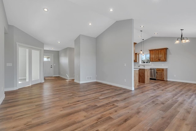 unfurnished living room featuring a chandelier, visible vents, baseboards, and light wood-style floors