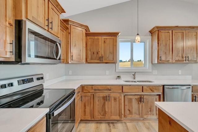 kitchen featuring a sink, vaulted ceiling, light countertops, and stainless steel appliances