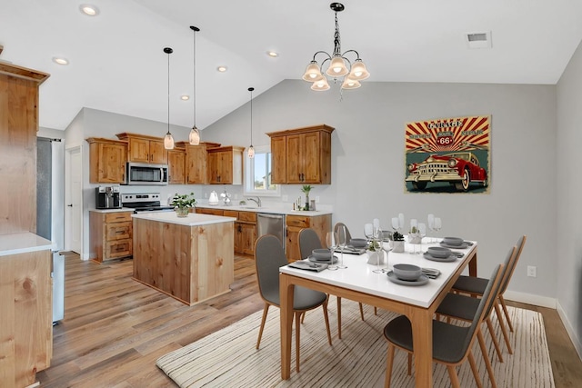 kitchen with light wood finished floors, visible vents, a kitchen island, light countertops, and appliances with stainless steel finishes