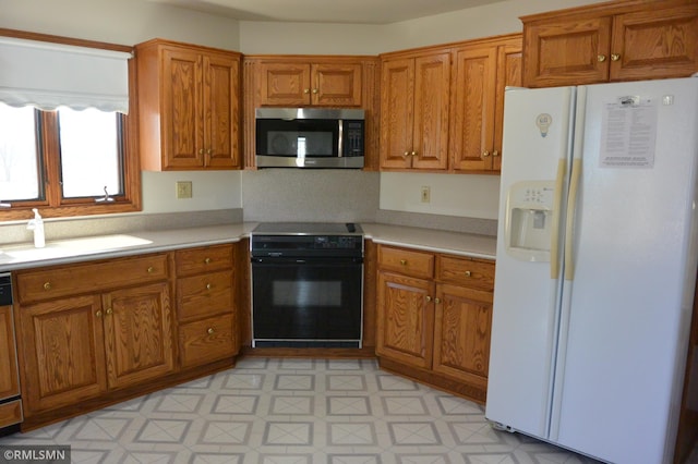 5501 70th St, Glencoe, MN 55336 - kitchen with white fridge with ice dispenser, stainless steel microwave, range, brown cabinetry, and a sink