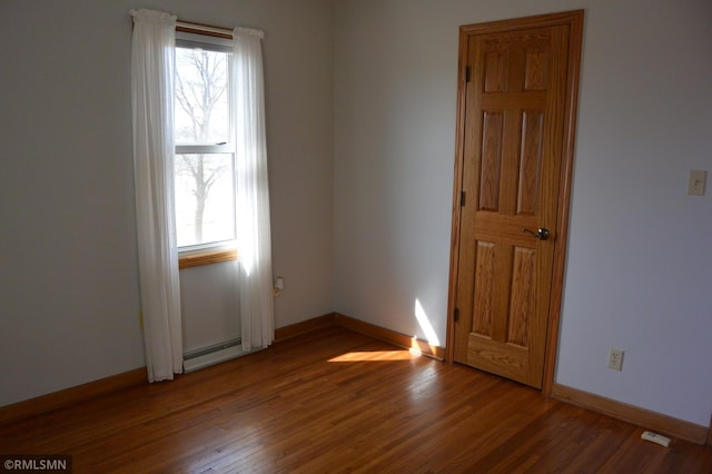 5501 70th St, Glencoe, MN 55336 - spare room featuring wood finished floors, a baseboard radiator, and baseboards