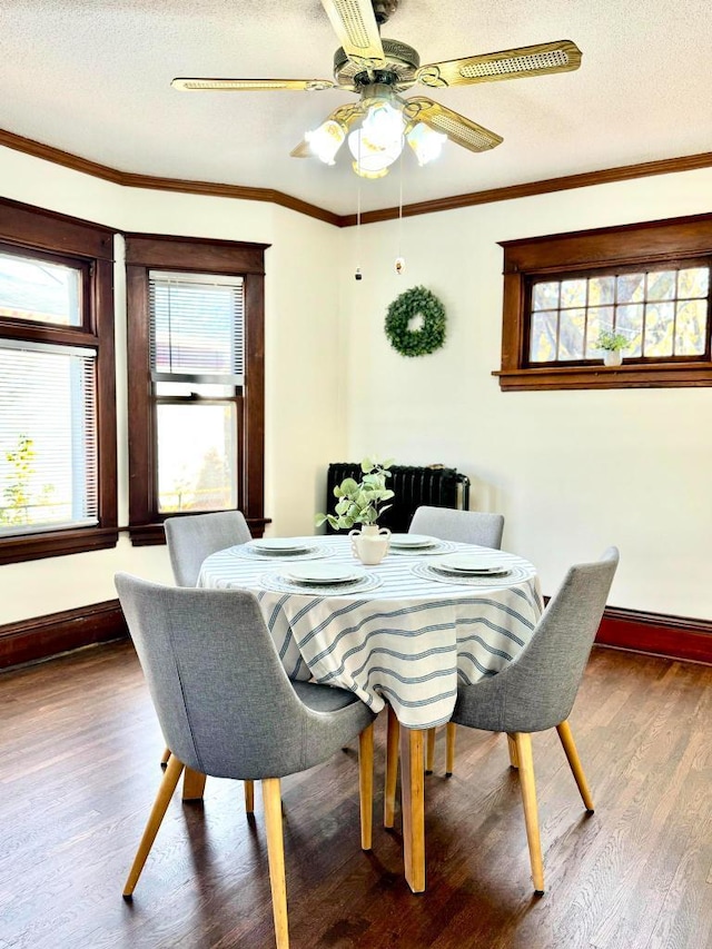 dining area featuring a textured ceiling, wood finished floors, baseboards, and ornamental molding