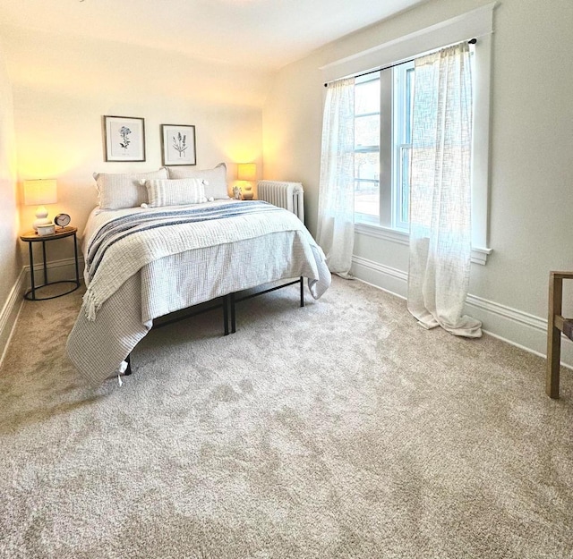 bedroom featuring baseboards, radiator, and carpet