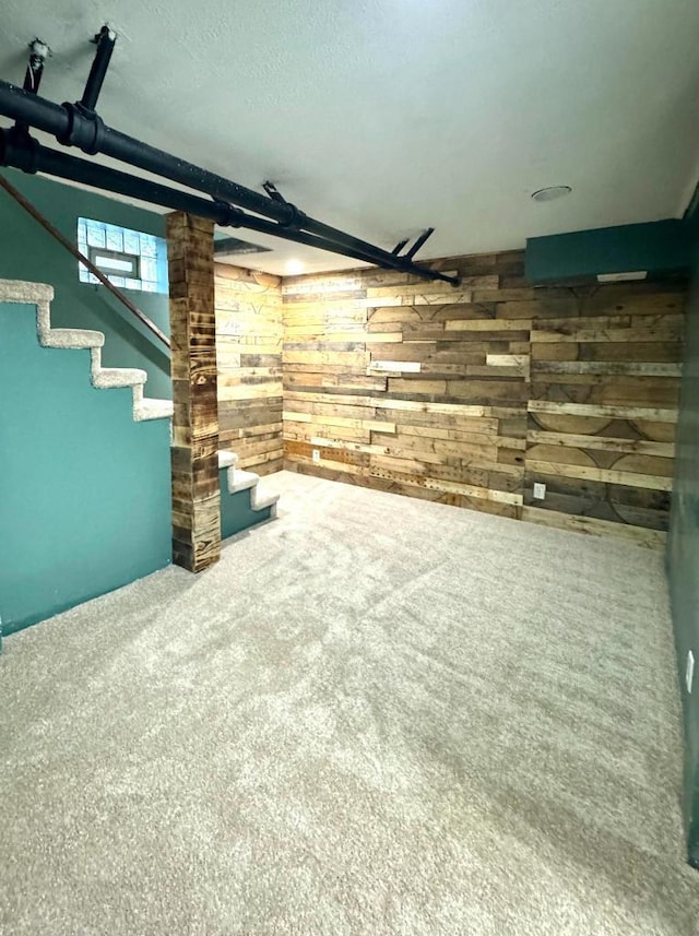 finished basement featuring wooden walls, stairway, and carpet