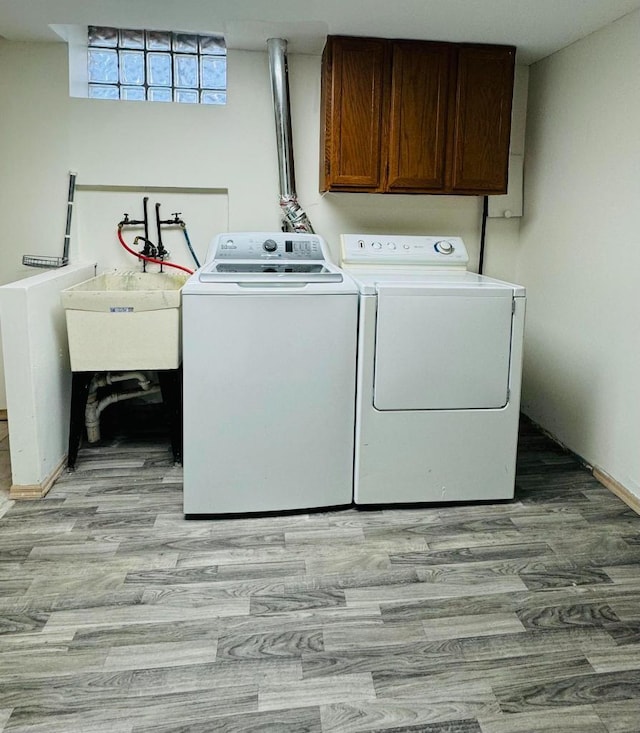 clothes washing area with washer and dryer, cabinet space, and light wood-type flooring