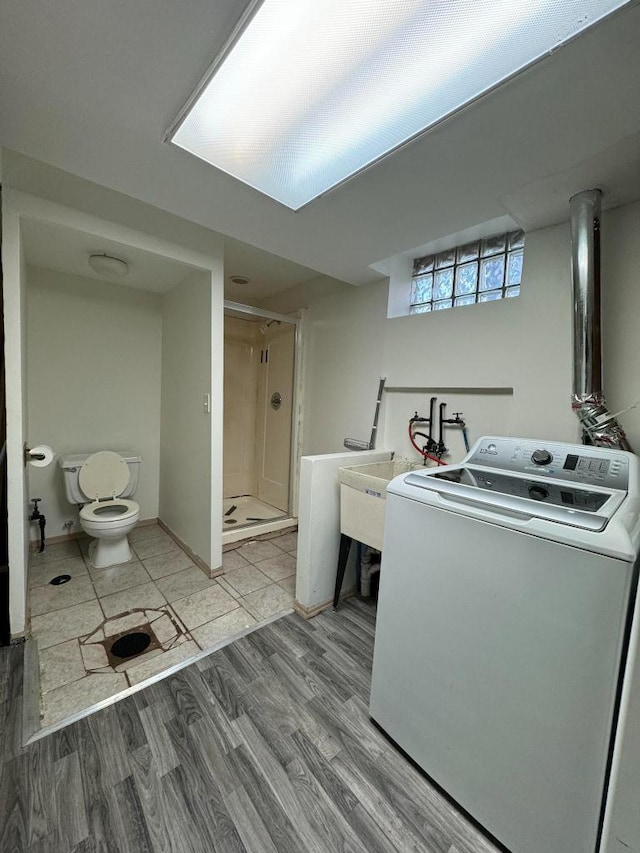 washroom with baseboards, laundry area, wood finished floors, washer / clothes dryer, and a sink