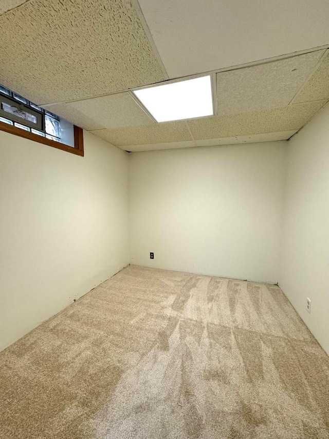 below grade area with a paneled ceiling and carpet