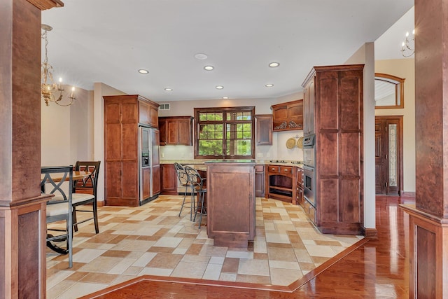 kitchen featuring a kitchen island, light countertops, a kitchen breakfast bar, stainless steel double oven, and paneled built in refrigerator