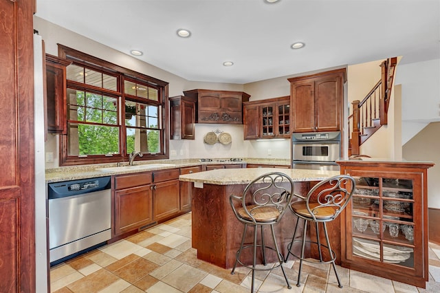 kitchen with glass insert cabinets, light stone countertops, recessed lighting, appliances with stainless steel finishes, and a sink