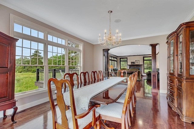 dining space with dark wood-style floors, arched walkways, crown molding, and decorative columns