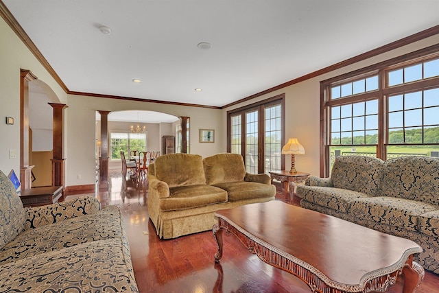 living area with arched walkways, wood finished floors, crown molding, and ornate columns