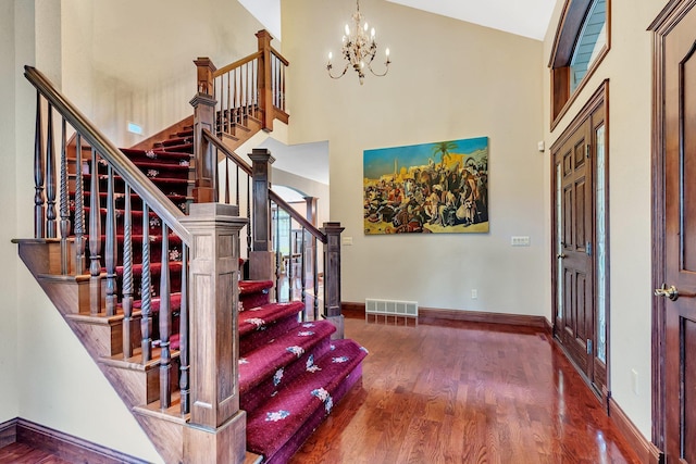 entryway featuring visible vents, baseboards, a towering ceiling, and wood finished floors