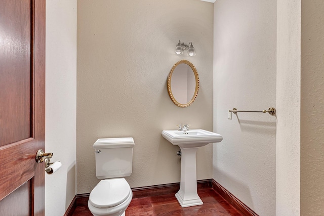 bathroom featuring toilet, wood finished floors, baseboards, and a sink