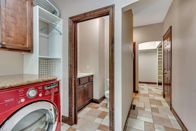 laundry room featuring stone finish floor, laundry area, washer / dryer, and baseboards