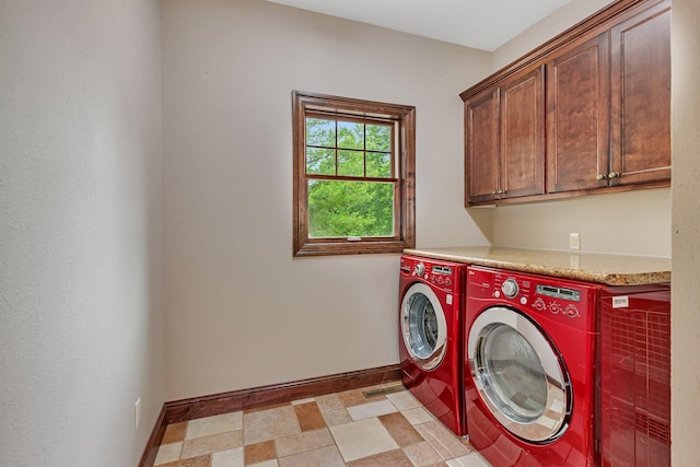 washroom with baseboards, cabinet space, light floors, and washing machine and dryer