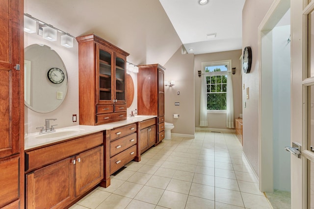 bathroom featuring toilet, a sink, tile patterned flooring, double vanity, and a bath