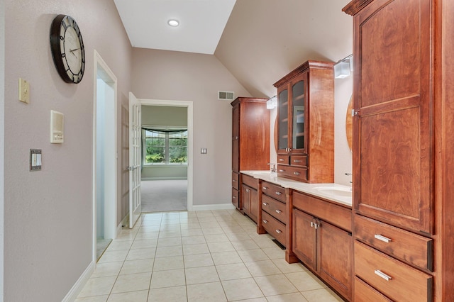 full bath featuring tile patterned flooring, visible vents, baseboards, lofted ceiling, and double vanity