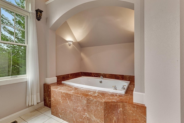 bathroom featuring tile patterned floors, baseboards, a garden tub, and vaulted ceiling