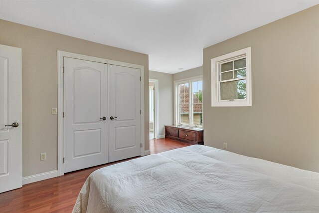 bedroom with wood finished floors, baseboards, and a closet