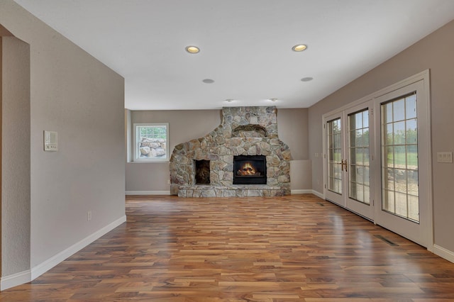 unfurnished living room with baseboards, wood finished floors, and a fireplace